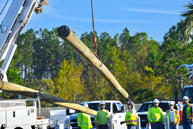 Crews loading poles onto trucks to repair damage caused by Hurricane Michael